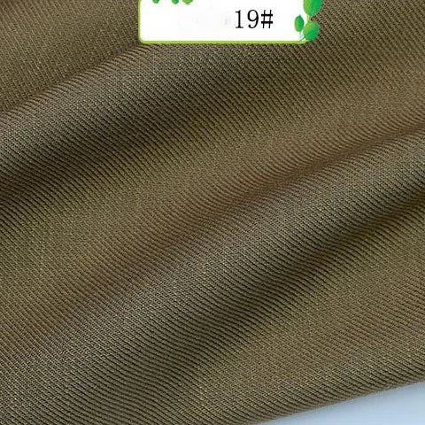 A close-up of Longan Craft’s Colorful Twill 100 Lyocell Fabric shows its brown, textured sustainable material with visible horizontal ridges and gentle folds. A small label marked 19# is seen at the top edge.