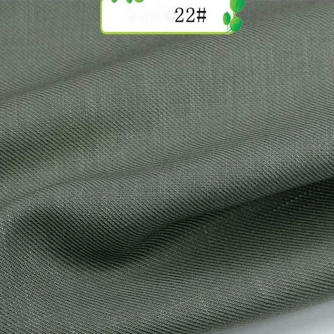 A close-up of Longan Craft’s Colorful Twill 100 Lyocell Fabric shows textured dark grey sustainable material with fine diagonal lines, gentle folds, and a "22#" label with green accents. Ideal for suits; sold by the yard.