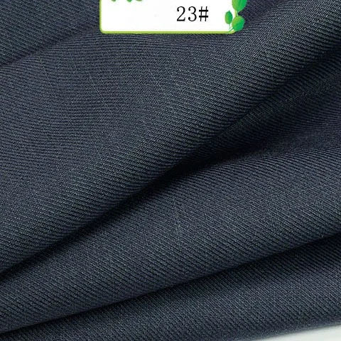 Close-up of folded dark navy blue Longan Craft Colorful Twill 100 Lyocell Fabric By The Yard shows its fine texture. A small label with green accents and the number 23# is visible at the top, highlighting this sustainable textile for suits.