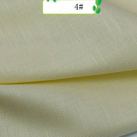 Close-up of Colorful Twill 100 Lyocell Fabric By The Yard from Longan Craft in light yellow, folded in soft layers. The sustainable lyocell textile has a subtle sheen and features a 4# label decorated with green leaves.
