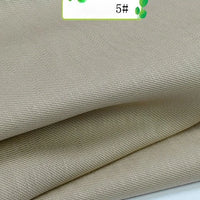 Close-up of Longan Craft’s Colorful Twill 100 Lyocell Fabric by the Yard, in light beige with a subtle diagonal weave, neatly folded and showing part of a 5# label—sustainable and ideal for suits.