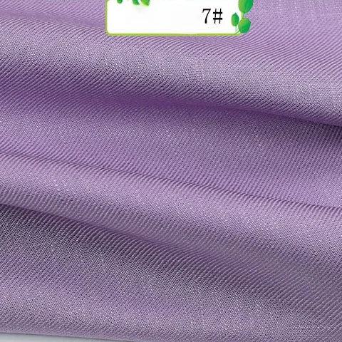A close-up shows folded Colorful Twill 100 Lyocell Fabric by the yard from Longan Craft, featuring textured lavender material with a soft sheen and a partially visible label marked 7# and green leaves, highlighting its sustainable comfort.