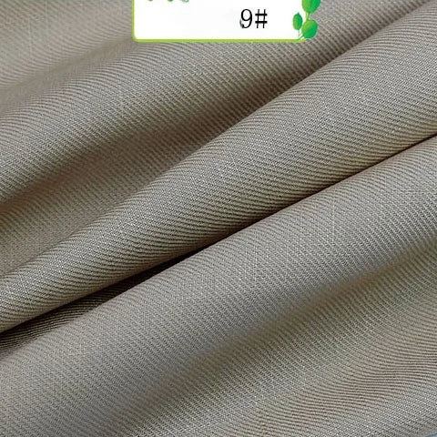 Close-up of Longan Craft Colorful Twill 100 Lyocell Fabric By The Yard shows subtle diagonal lines and soft folds. A partial label with green and black text appears at the top, highlighting this sustainable textile for suits.