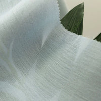 A close-up of Longan Craft’s Colorful Viscose Challis Fabric By The Yard, a lightweight, breathable polyester viscose material with a subtle pattern, softly draped over green leaves and ideal for sun protection shirts.