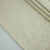 A close-up of Longan Craft’s Cotton Damask Fabric By The Yard reveals its intricate antique floral jacquard pattern. Neatly folded in the corner, this cotton-polyester blend showcases an elegant, wrinkle-resistant finish.