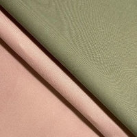 Close-up of two folded Longan Craft Cotton Gabardine Fabric By The Yard, lightweight twill texture, in muted sage green and soft blush pink, laid diagonally to showcase breathable gabardine material for shirt making.