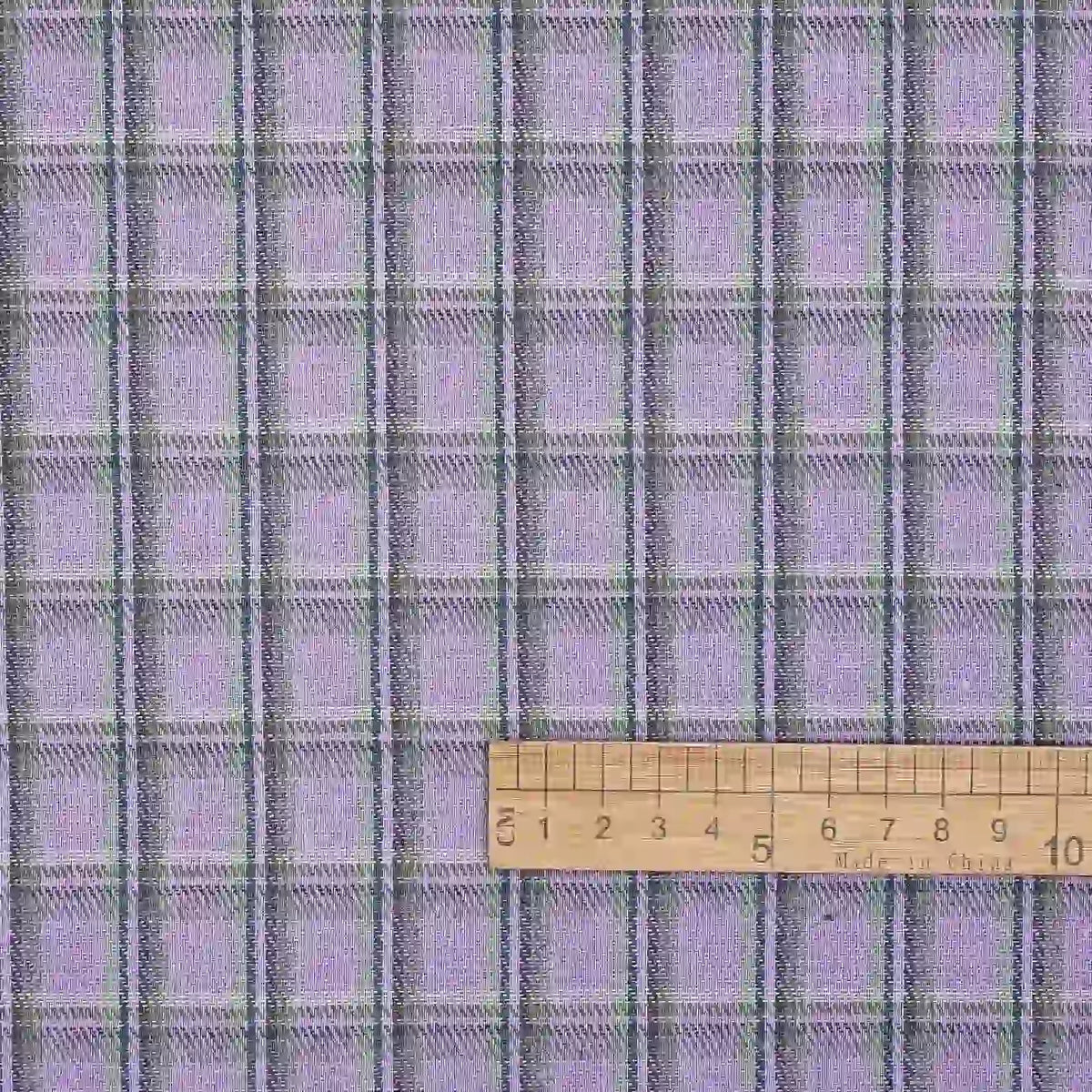 Here’s the revised sentence using your product data: The Longan Craft Cotton Gingham Sueded Flannel Fabric By The Yard features a multicolor plaid pattern with thin black and green stripes on a soft, comfy sueded flannel material. A wooden ruler marked in centimeters is placed horizontally at the bottom for scale.