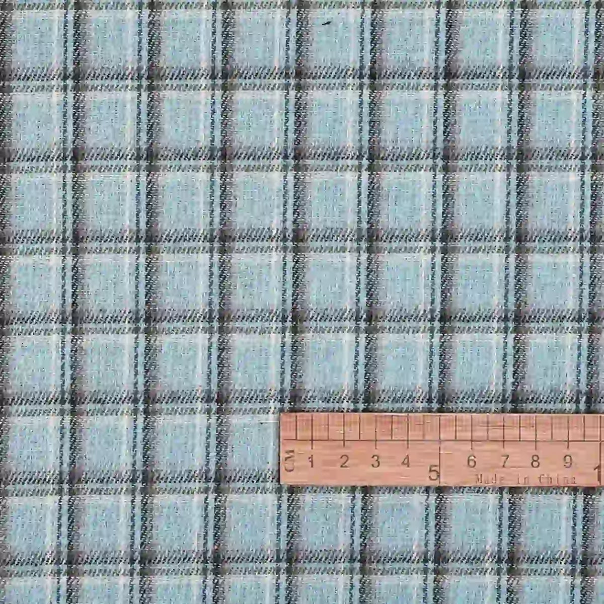 A yard of Longan Craft’s Cotton Gingham Sueded Flannel Fabric, featuring a comfy multicolor checked polyester design, is shown with a wooden ruler in inches for scale to indicate the size of the pattern.
