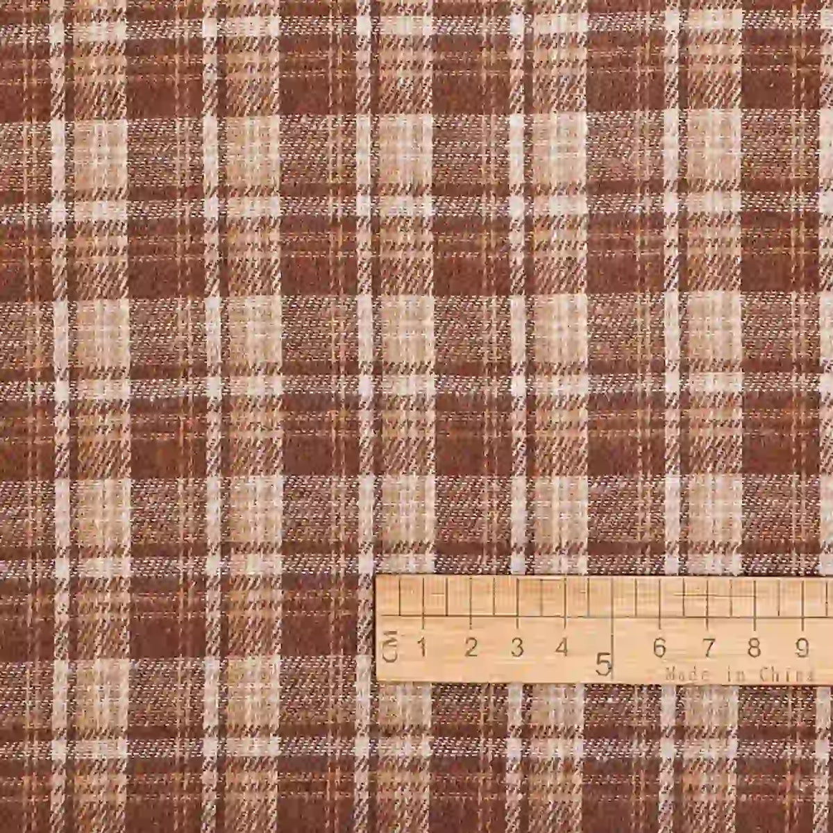 The Cotton Gingham Sueded Flannel Fabric By The Yard from Longan Craft features a multicolor polyester checked design in shades of brown, tan, and cream with intersecting vertical and horizontal lines. A wooden ruler in centimeters appears at the bottom right to indicate the scale of this comfy shirting flannel material.