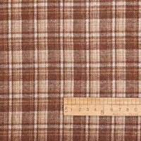 The Cotton Gingham Sueded Flannel Fabric By The Yard from Longan Craft features a multicolor polyester checked design in shades of brown, tan, and cream with intersecting vertical and horizontal lines. A wooden ruler in centimeters appears at the bottom right to indicate the scale of this comfy shirting flannel material.