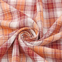 Close-up of Longan Craft’s Cotton Jacquard Plaid Flannel Fabric by the yard, featuring a swirl display of its cozy, one-sided brushed checked texture in warm orange, rust, and cream hues—highlighting the intersecting lines of its classic autumn plaid design.