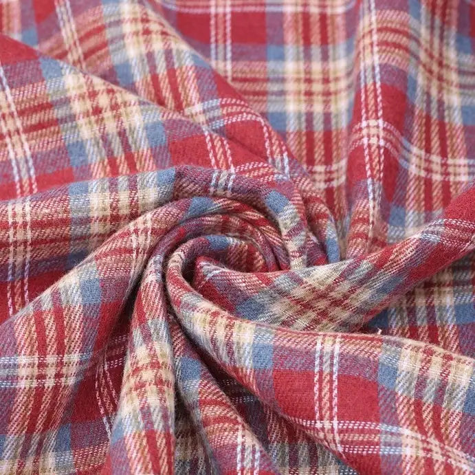 The Cotton Jacquard Plaid Flannel Fabric by the yard from Longan Craft is displayed in a swirl, highlighting its one-sided brushed, soft texture and classic red, blue, and beige checkered pattern—perfect for cozy autumn clothing.