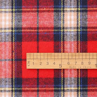 A wooden ruler marked “Made in China” measures approximately 7 centimeters as it rests on Longan Craft’s Cotton Jacquard Plaid Flannel Fabric By The Yard, a cozy autumn material featuring a red base with blue, yellow, and white stripes in a checked jacquard weave.