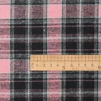 A wooden ruler measures in centimeters atop Longan Craft’s Cotton Jacquard Plaid Flannel Fabric By The Yard—a cozy, one-sided brushed checked flannel material featuring classic intersecting tartan lines, perfect for autumn clothing.