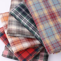 Five pieces of Longan Craft Cotton Jacquard Plaid Flannel Fabric by the yard, featuring a one-sided brushed checked design in assorted colors and patterns, are stacked together to highlight their soft texture and cozy appearance—perfect for autumn clothing projects.