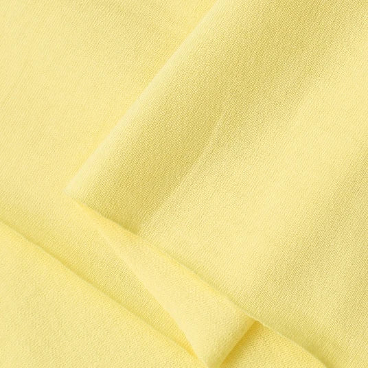 Close-up of Longan Craft Cotton Jersey Fabric By The Yard shows its soft, lightweight texture and light yellow color. This 100% cotton single jersey material is breathable and ideal for making casual wear.