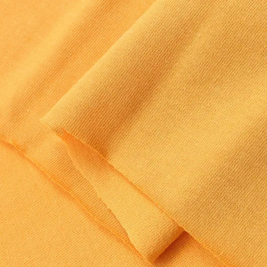 Close-up of Longan Craft Cotton Jersey Fabric By The Yard in a soft, light orange shade, highlighting its smooth texture and fine knit—ideal colorful single jersey material for casual wear.
