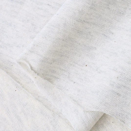 A close-up of Longan Craft's Cotton Jersey Fabric By The Yard reveals its soft, slightly textured surface in light grey heather, perfect for making casual wear.