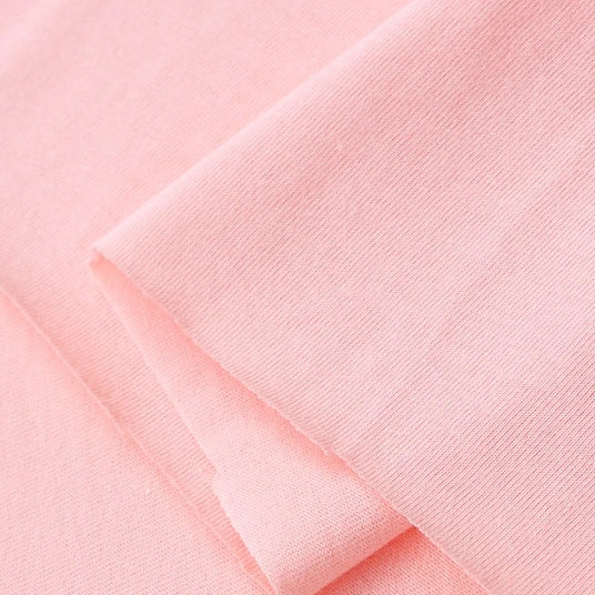 Close-up of Longan Craft’s Cotton Jersey Fabric by the Yard, a soft, colorful single jersey material in light pink 100% cotton, featuring a smooth texture, neatly folded edges, and a subtle weave—ideal for casual wear.