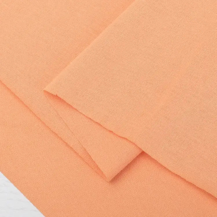 Two overlapping pieces of Longan Craft Cotton Jersey Fabric By The Yard in peach color are laid flat, displaying a smooth texture, clean edges, and the breathable quality of this 100% cotton single jersey material for casual wear.