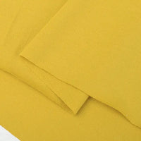 A close-up of Longan Craft's Cotton Jersey Fabric By The Yard—shown in mustard yellow with a slightly textured surface—ideal for casual wear and colorful single jersey projects.
