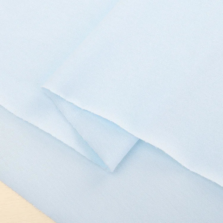 A close-up of Longan Craft's Cotton Jersey Fabric By The Yard, a soft jersey material in light blue with slightly frayed edges, ideal for casual wear and crafts.