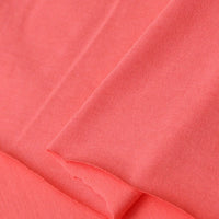 Close-up of Longan Craft Cotton Jersey Fabric by the yard in coral pink, showing its smooth, soft texture and visible weave. This breathable, colorful single jersey material is perfect for making casual wear.