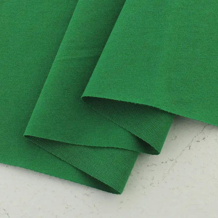 Two pieces of Longan Craft Cotton Jersey Fabric By The Yard, a colorful and soft single jersey ideal for casual wear, are partially overlapped on a light, speckled background.