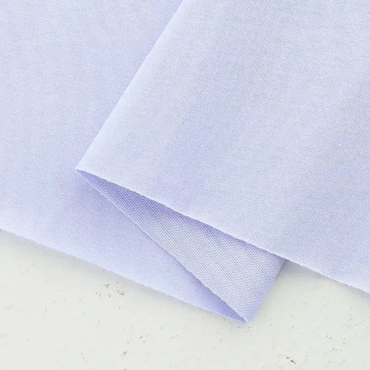 A close-up of Longan Craft's Cotton Jersey Fabric By The Yard, neatly folded on a white surface, highlights its smooth, soft texture and breathable quality—ideal colorful single jersey material for making casual wear.