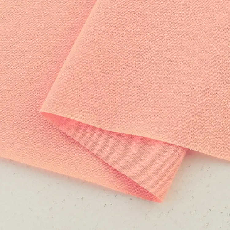 A close-up of two overlapping pieces of Longan Craft Cotton Jersey Fabric By The Yard in light pink, showcasing the soft, smooth, and breathable single jersey material—ideal for creating comfortable casual wear.