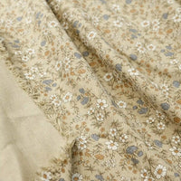 Longan Craft’s Daisy Print 16 Wale Corduroy Fabric by the yard features a fine wale, 100% cotton corduroy material in beige with a delicate floral design of white, blue, and brown flowers with green stems. This fall-inspired DIY fabric offers a soft, textured surface and has one edge slightly frayed to reveal the fabric’s underside.