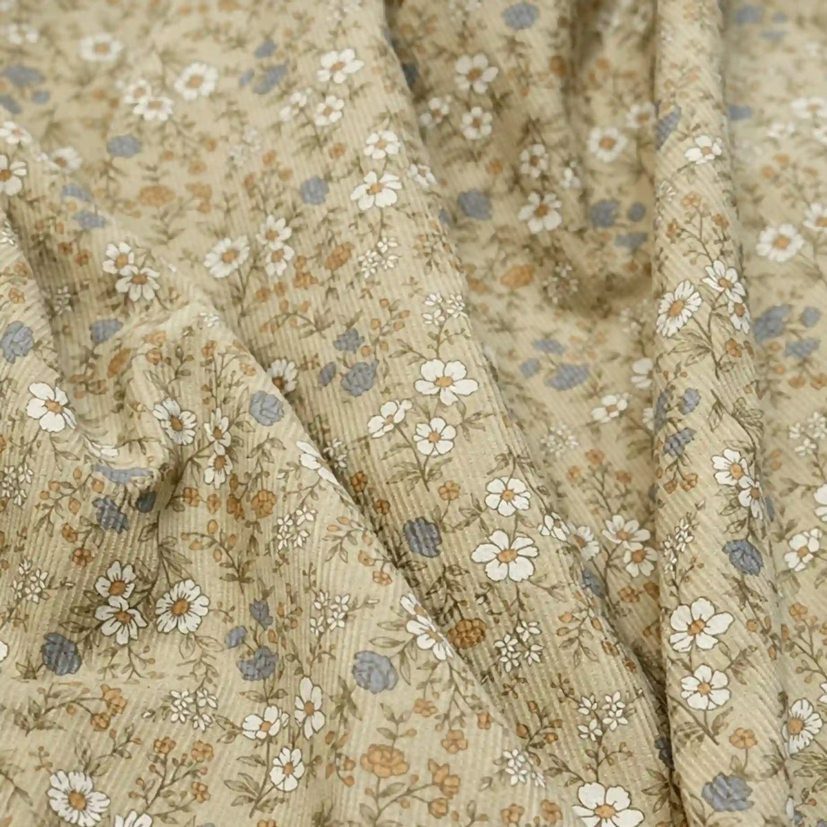 Close-up of Longan Craft’s Daisy Print 16 Wale Corduroy Fabric By The Yard, a soft, fine wale 100% cotton corduroy material in beige featuring a delicate floral pattern of small white, blue, and brown flowers with green stems—perfect for fall DIY projects.