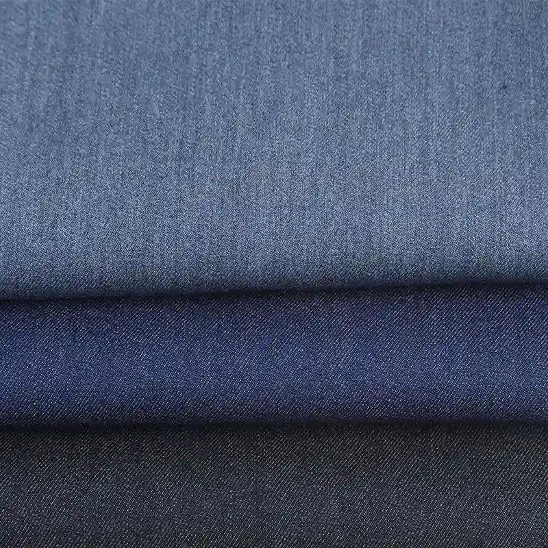Three folded pieces of Longan Craft Denim Color Twill Viscose Fabric in light, medium, and dark blue—chic stretch elastane material by the yard, perfect for stylish tailored trousers and dressmaking.