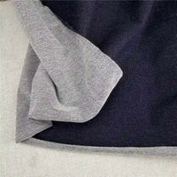 A close-up of Longan Craft’s Denim French Terry Fabric by the Yard, a navy blue 100% cotton knit with a light gray inner lining, partially folded to show both sides. This soft solid-color material is perfect for stylish, comfortable pants.