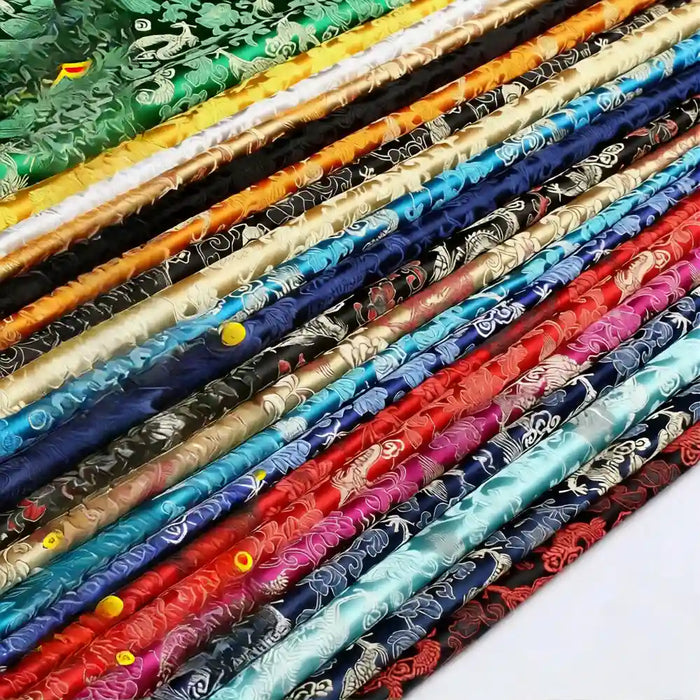 Stacks of Longan Craft’s Dragon Pattern Brocade Fabric By The Yard, featuring vintage chinoiserie motifs in vibrant multicolor floral, swirling, and dragon designs. Perfect brocade material for crafts or decor.