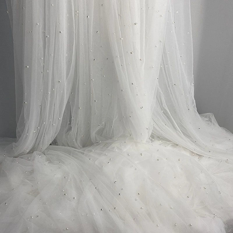 The Elegant Pearl Embellished Tulle Fabric by Longan Craft features solid color sheer material with pearl-like beads—lightweight and perfect for dreamy evening dresses, weddings, or any project needing an elegant touch. Sold by the yard.
