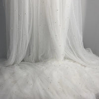The Elegant Pearl Embellished Tulle Fabric by Longan Craft features solid color sheer material with pearl-like beads—lightweight and perfect for dreamy evening dresses, weddings, or any project needing an elegant touch. Sold by the yard.