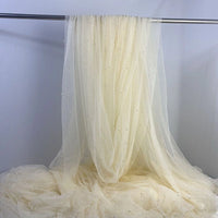 Elegant Pearl Embellished Tulle Fabric by Longan Craft drapes beautifully over a rod, pooling gently on a light backdrop. This sheer, lightweight fabric is perfect for wedding gowns or evening dresses. Available by the yard.