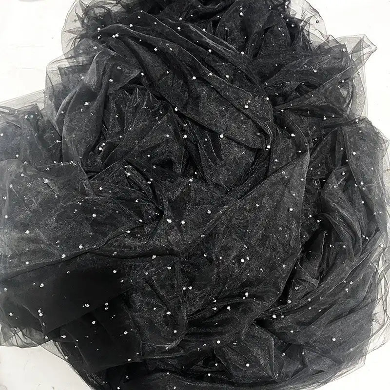 A close-up of Elegant Pearl Embellished Tulle Fabric by Longan Craft shows black sheer tulle with scattered white pearls, offering a textured, elegant look ideal for evening dresses or wedding decor.