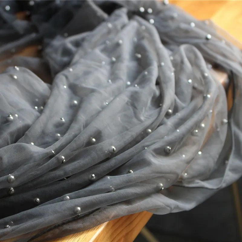 A close-up of Elegant Pearl Embellished Tulle Fabric By The Yard from Longan Craft, a solid color sheer tulle with pearl-like beads—lightweight material perfect for wedding gowns or evening dresses.