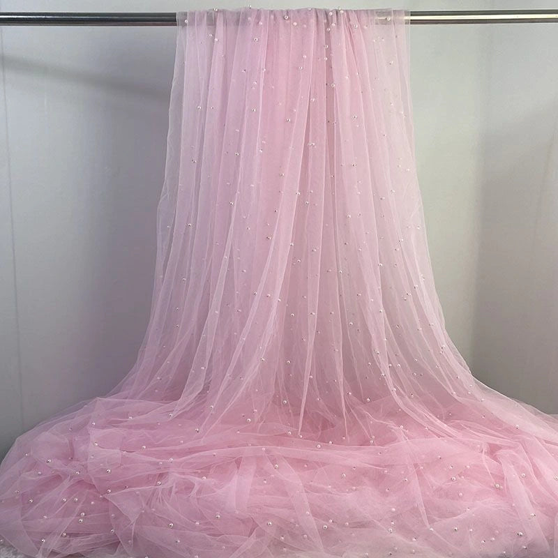 Longan Craft's Elegant Pearl Embellished Tulle Fabric By The Yard features sheer tulle with white pearls, draped beautifully—ideal for bridal gowns or elegant evening dresses. This lightweight, solid color fabric is perfect for wedding creations.