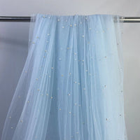 The Elegant Pearl Embellished Tulle Fabric by Longan Craft features sheer, light blue tulle adorned with evenly spaced pearl-like beads, draped over a metal rod and set against a plain light gray background.