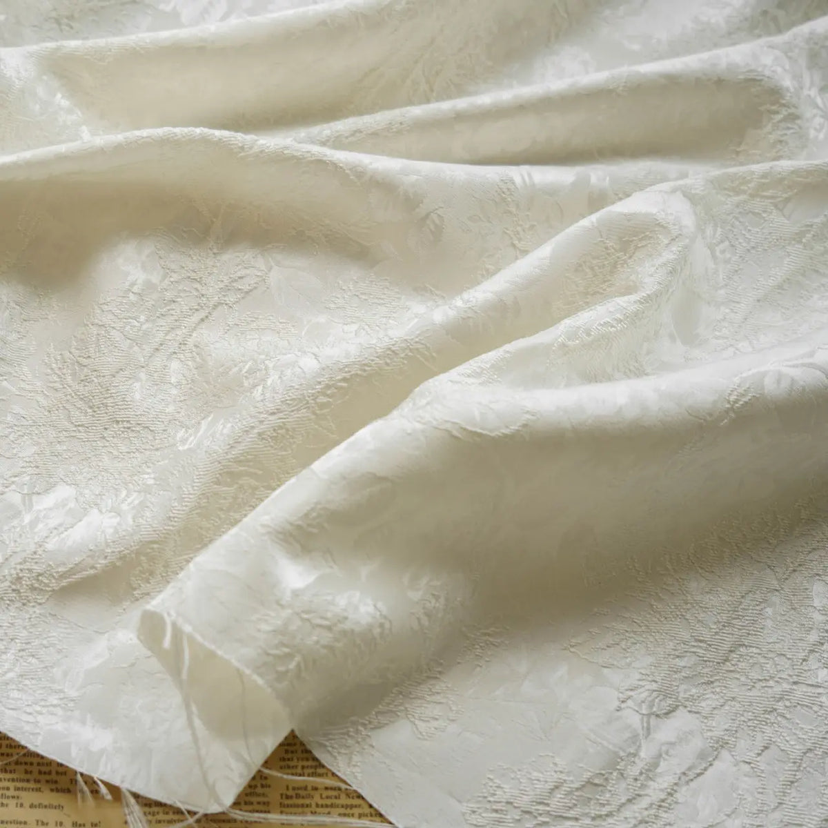 A close-up of Embossed Peony Brocade Fabric by Longan Craft draped in soft folds, highlighting its elegant jacquard floral pattern and textured finish—a Chinese style material ideal for dresses.