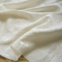 A close-up of Embossed Peony Brocade Fabric by Longan Craft draped in soft folds, highlighting its elegant jacquard floral pattern and textured finish—a Chinese style material ideal for dresses.