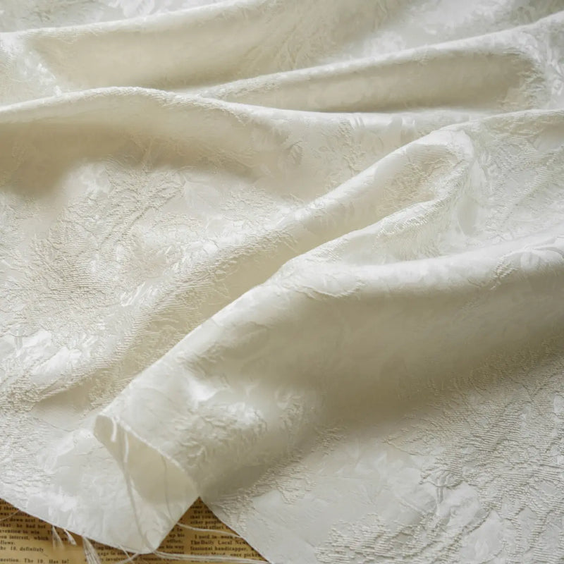 A close-up of Embossed Peony Brocade Fabric by Longan Craft draped in soft folds, highlighting its elegant jacquard floral pattern and textured finish—a Chinese style material ideal for dresses.