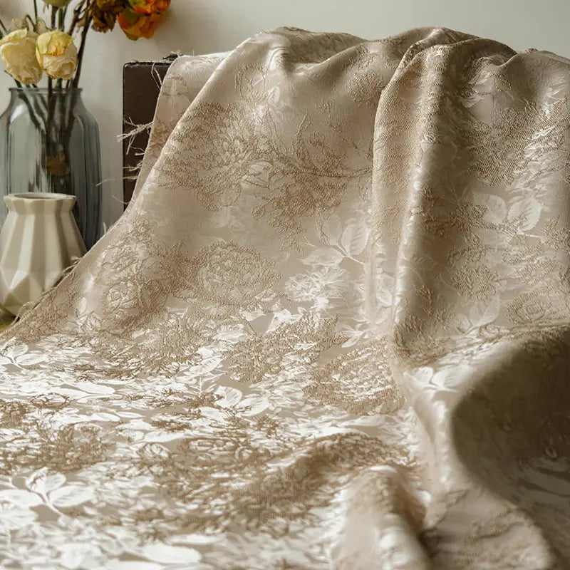 A close-up of Longan Craft's Embossed Peony Brocade Fabric by the Yard, a Chinese-style floral fabric for dresses, draped gracefully with glass and ceramic vases holding dried flowers in the background.