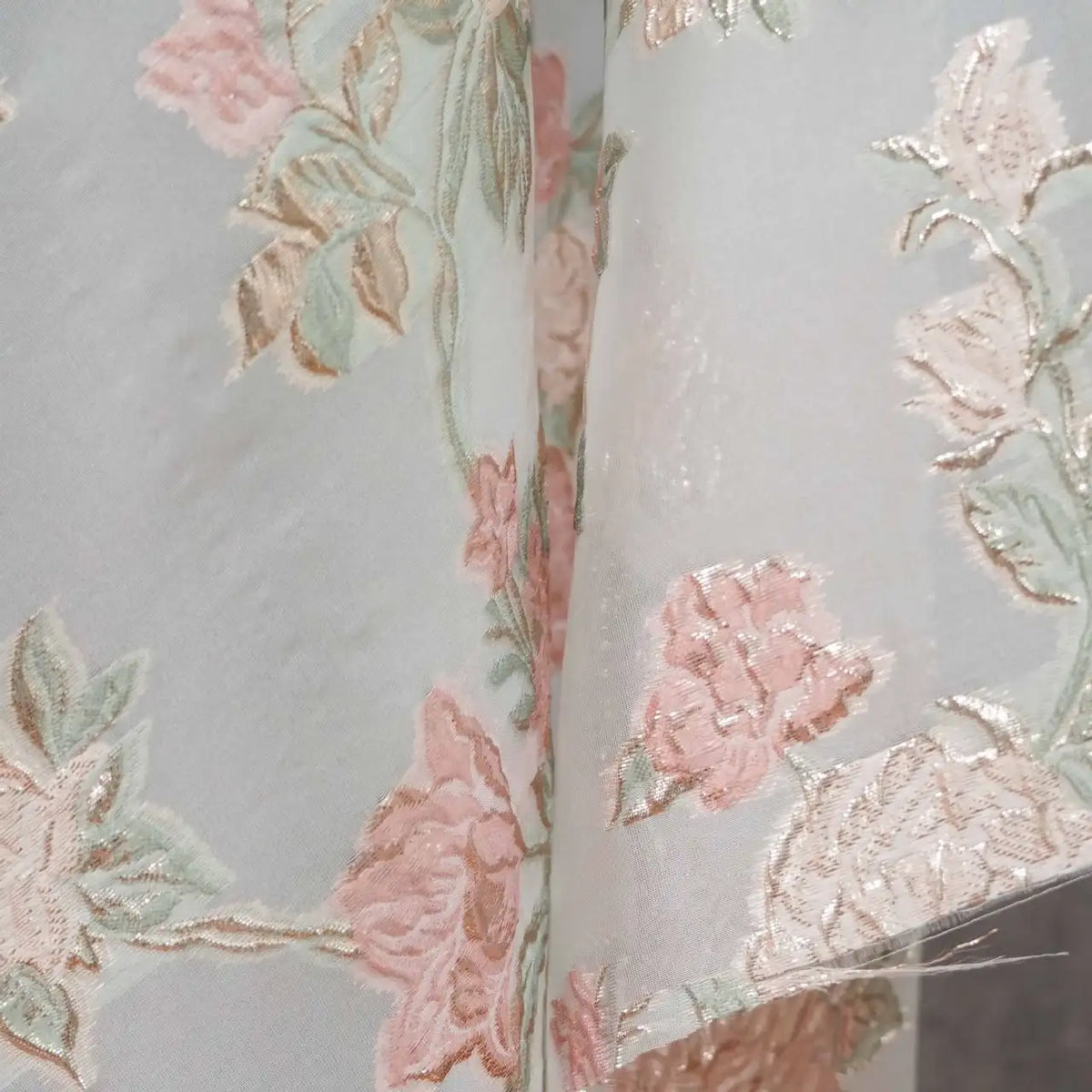 Close-up of Longan Craft’s Embossed Rose Organza Fabric—a sheer, lightweight fabric with gold floral jacquard pattern on a silvery background. Ideal for camisole tops, it has a subtle sheen that highlights the delicate rose design.