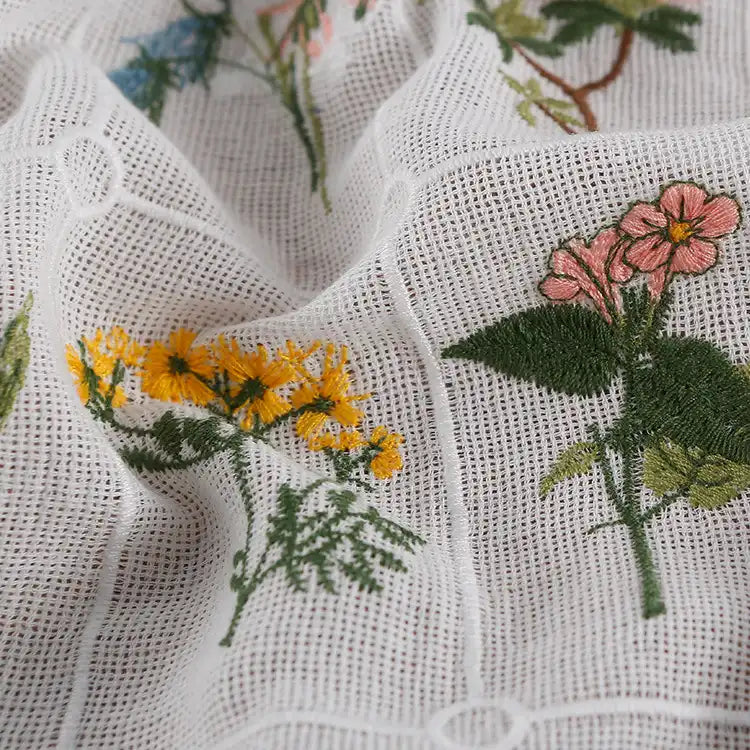 Close-up of Longon Craft’s Plant Floral Embroidered Cotton Fabric By The Yard, featuring colorful flower embroidery—yellow, pink blooms, and green leaves—on soft wrinkled grid cotton. Perfect for apparel and crafts.