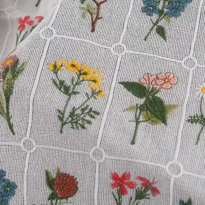 Close-up of Longon Craft’s Plant Floral Embroidered Cotton Fabric by the yard—a soft grid cotton material featuring colorful embroidered flowers in each square, ideal for apparel.