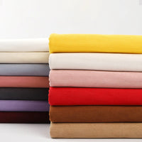 A neatly stacked pile of Longan Craft 16 Wales Fine Wale Corduroy Fabric in solid yellow, white, pink, red, brown, gray, and purple—perfect for DIY sofa covers, clothing, and pants—is displayed against a plain white background.